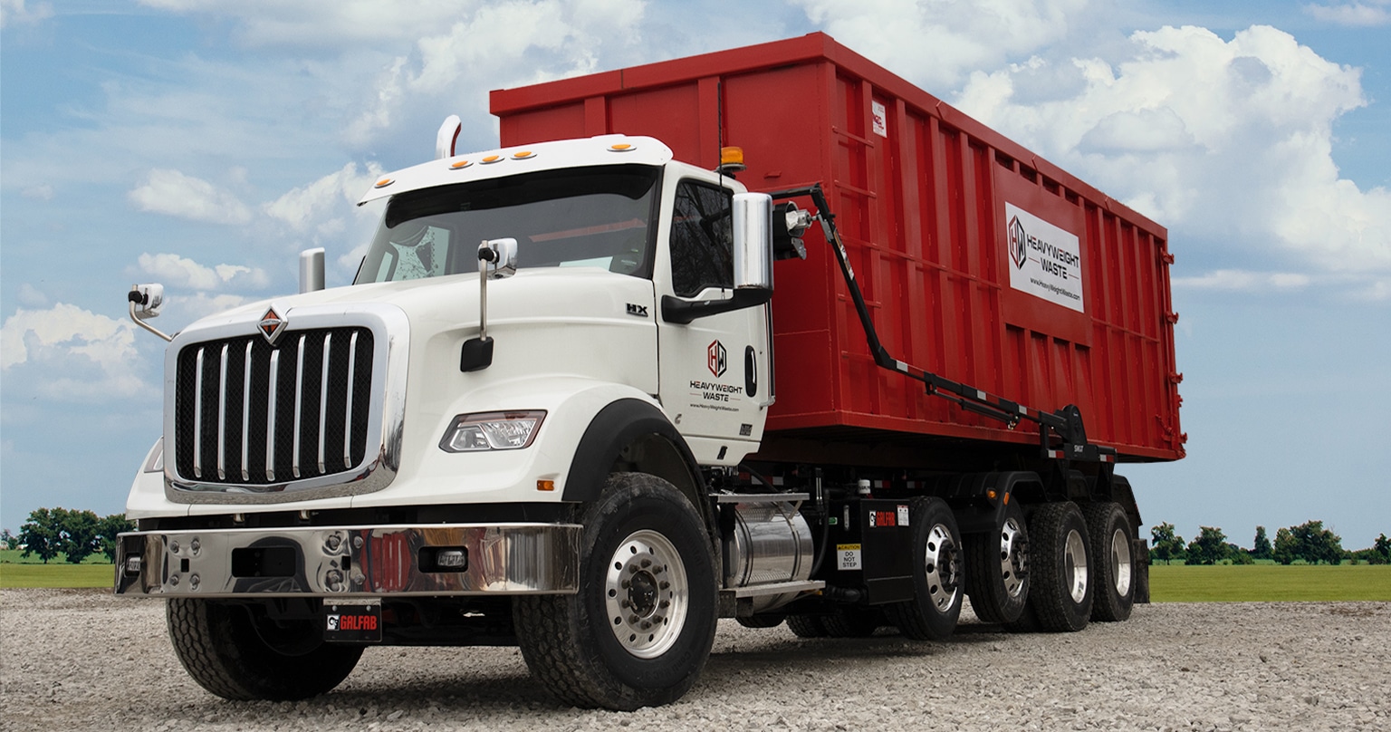 Heavyweight Waste roll-off dumpster truck parked against open sky background